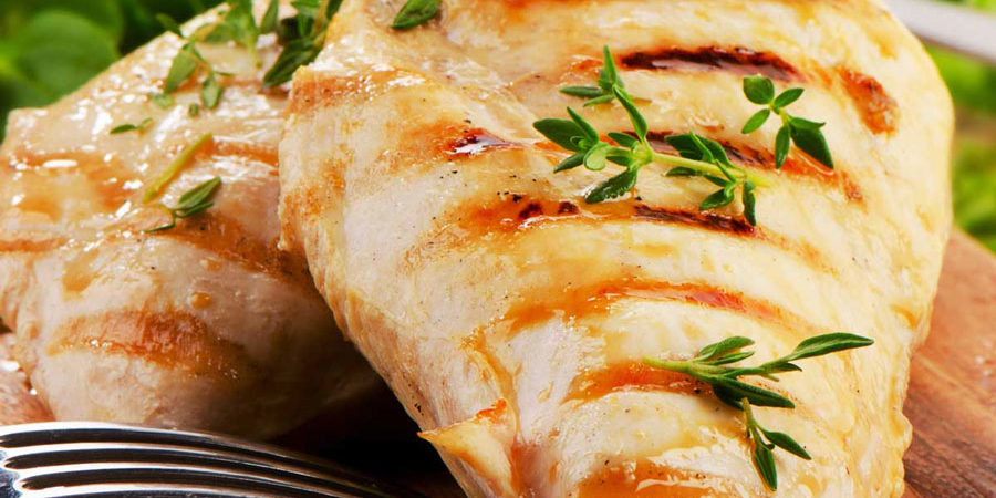 cooked chicken breast on cutting board with herbs